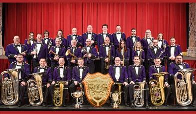 A picture of the Brighouse and Rastrick Band onstage, holding their instruments