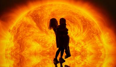 Silhouette of two children embracing against a vibrant, backdrop. 