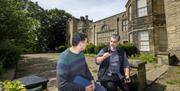 Two men talking in the grounds of a manor house
