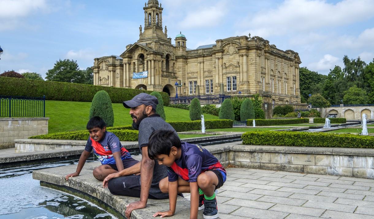 People looking into a pond outside a large manor house