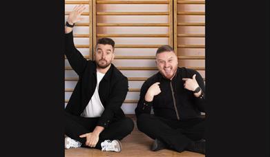 A picture of two men sitting on the floor in a school gym